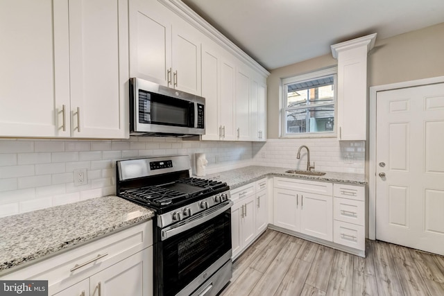 kitchen with light stone countertops, white cabinetry, sink, and appliances with stainless steel finishes