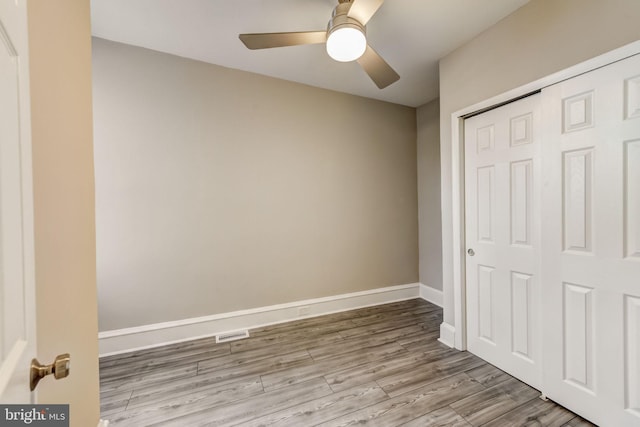 unfurnished bedroom featuring ceiling fan, light wood-type flooring, and a closet