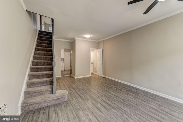 stairs featuring hardwood / wood-style flooring, ceiling fan, and crown molding