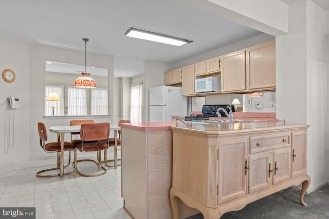 kitchen with kitchen peninsula, light brown cabinetry, white appliances, sink, and pendant lighting