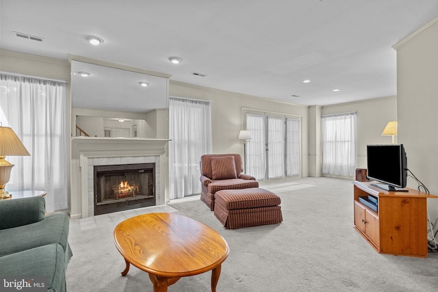 carpeted living room with crown molding and a tiled fireplace