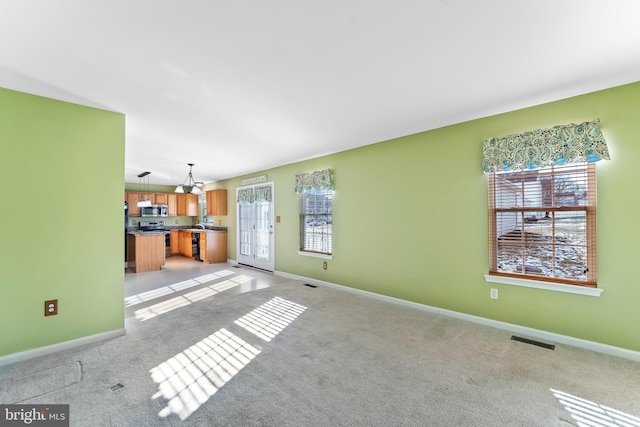 unfurnished living room with a notable chandelier and light carpet