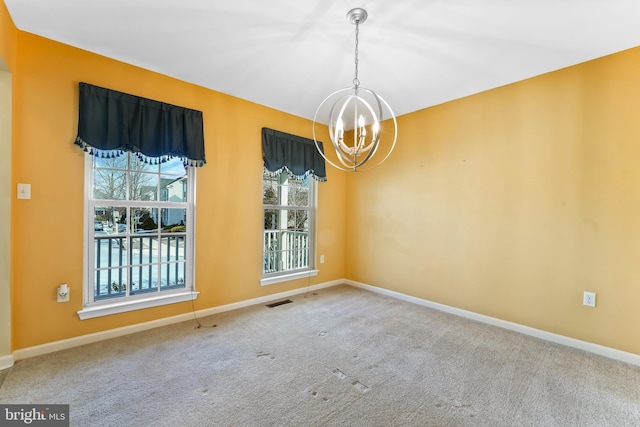 spare room with carpet floors and a chandelier