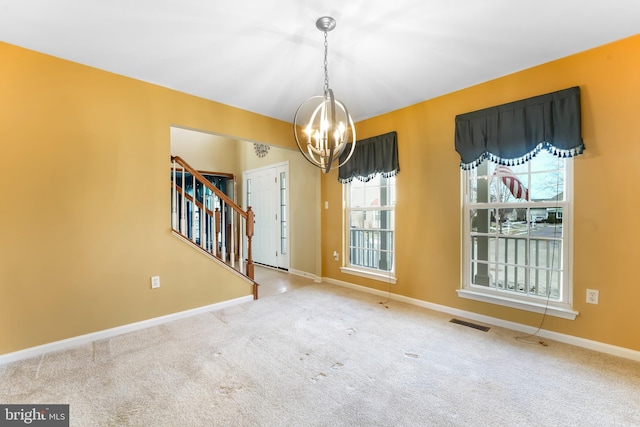 carpeted spare room with an inviting chandelier and a healthy amount of sunlight