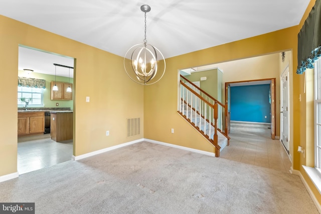 empty room with an inviting chandelier and light carpet