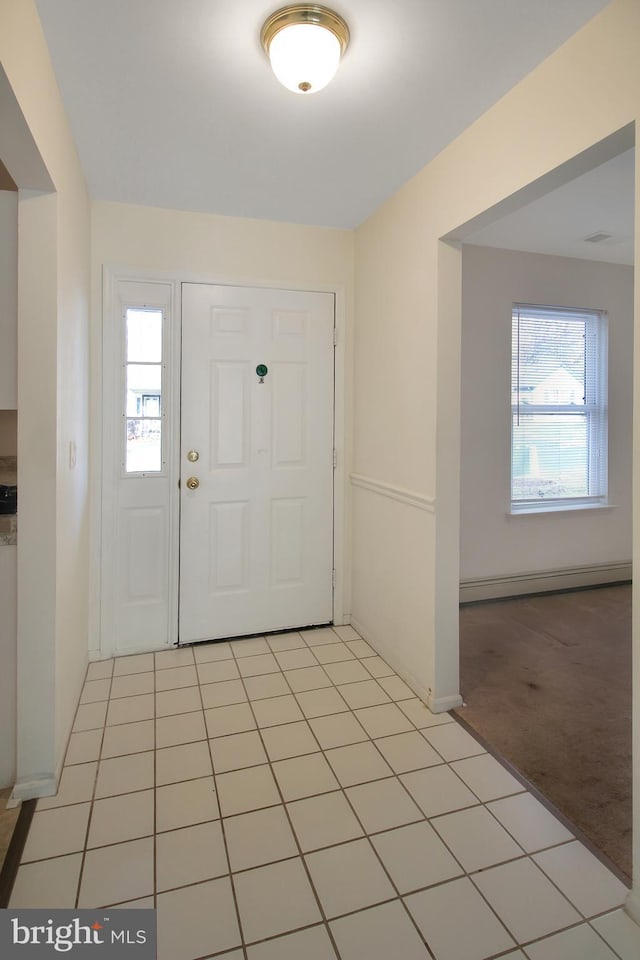 foyer entrance featuring a baseboard heating unit, light colored carpet, and a healthy amount of sunlight