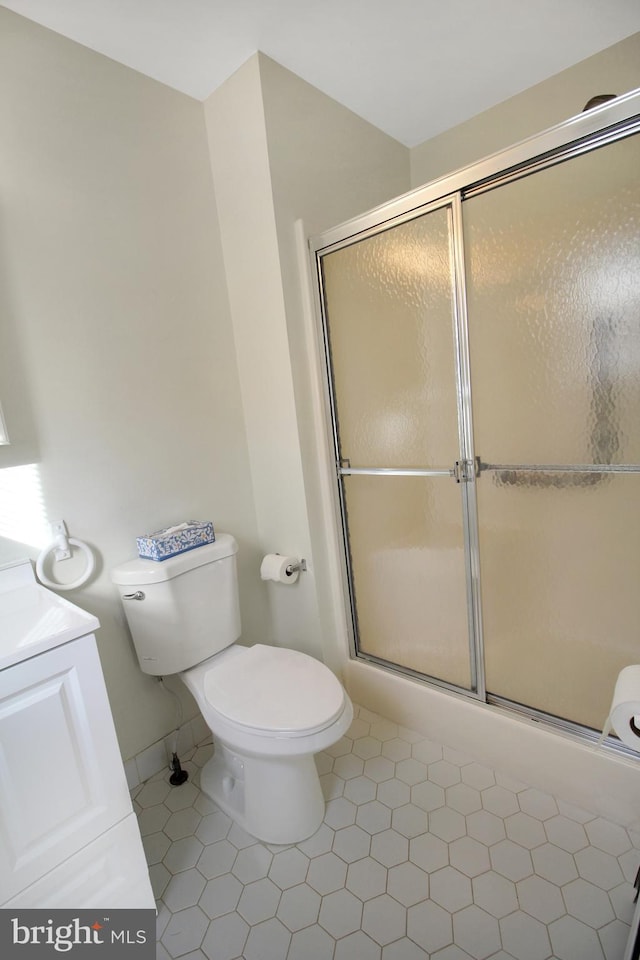 bathroom featuring tile patterned flooring, vanity, a shower with shower door, and toilet