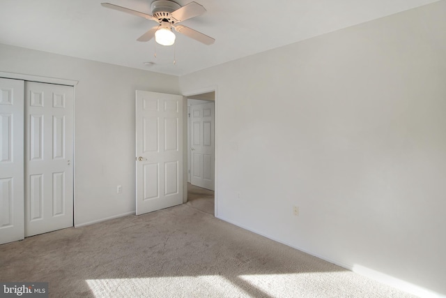 unfurnished bedroom featuring ceiling fan, a closet, and light carpet