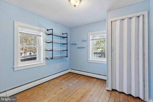 unfurnished room with light wood-type flooring and a baseboard heating unit