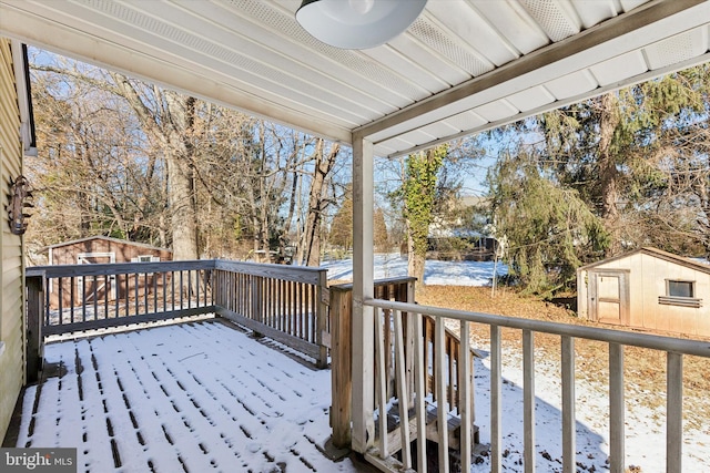 snow covered deck with a storage shed