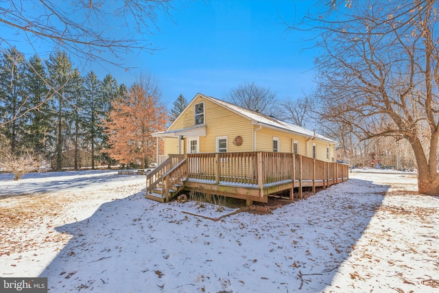 snow covered house with a wooden deck