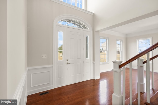 entryway with ornamental molding and dark wood-type flooring