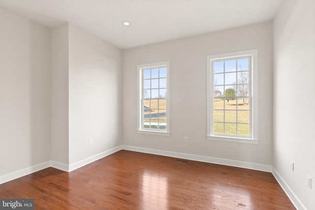 spare room featuring dark hardwood / wood-style flooring and a wealth of natural light