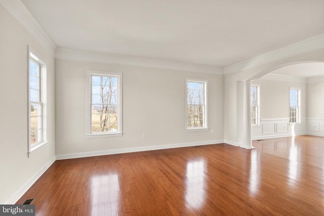 unfurnished room featuring decorative columns, ornamental molding, and light hardwood / wood-style flooring