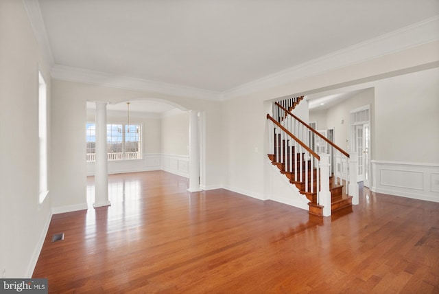 spare room with decorative columns, crown molding, and hardwood / wood-style floors