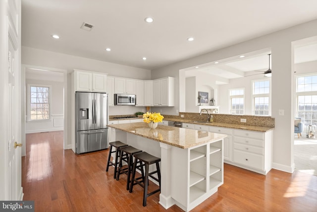 kitchen featuring sink, a breakfast bar, appliances with stainless steel finishes, white cabinetry, and a kitchen island