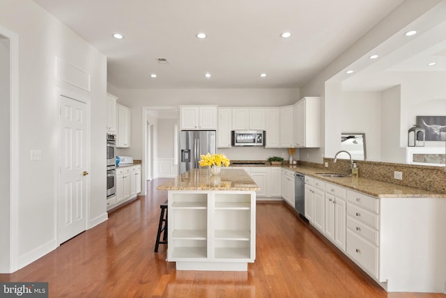 kitchen with white cabinetry, sink, stainless steel appliances, and kitchen peninsula