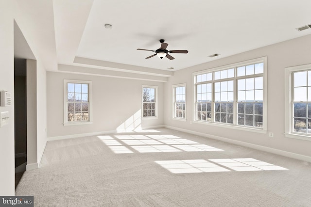 empty room with a wealth of natural light, light colored carpet, and ceiling fan