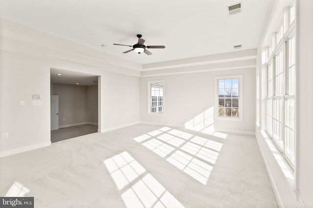 carpeted empty room featuring a raised ceiling and ceiling fan