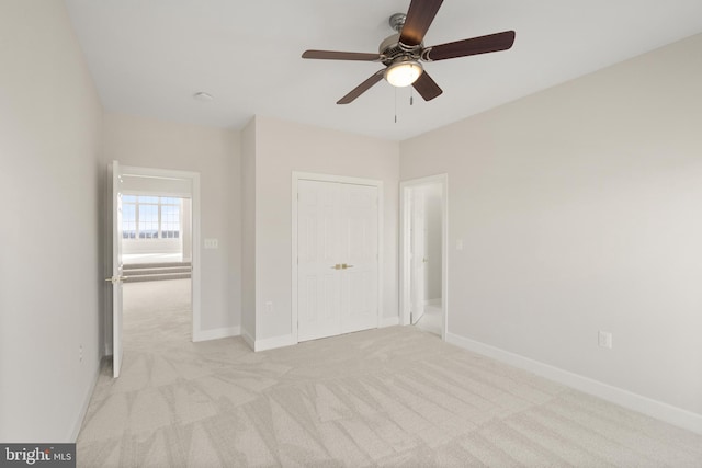 unfurnished bedroom featuring ceiling fan, a closet, and light carpet