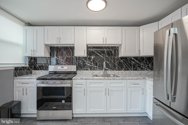 kitchen featuring white cabinets, sink, decorative backsplash, light stone countertops, and stainless steel appliances