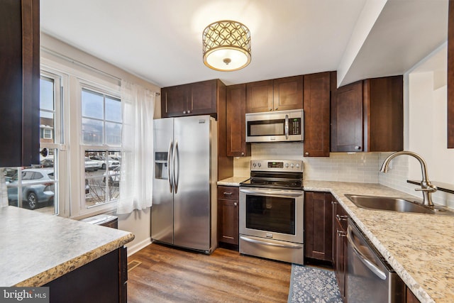 kitchen with appliances with stainless steel finishes, decorative backsplash, light hardwood / wood-style floors, and sink