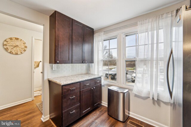 kitchen with tasteful backsplash, dark wood-type flooring, stainless steel refrigerator, and dark brown cabinetry