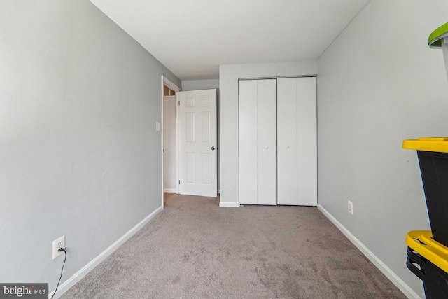 unfurnished bedroom with a closet and light colored carpet