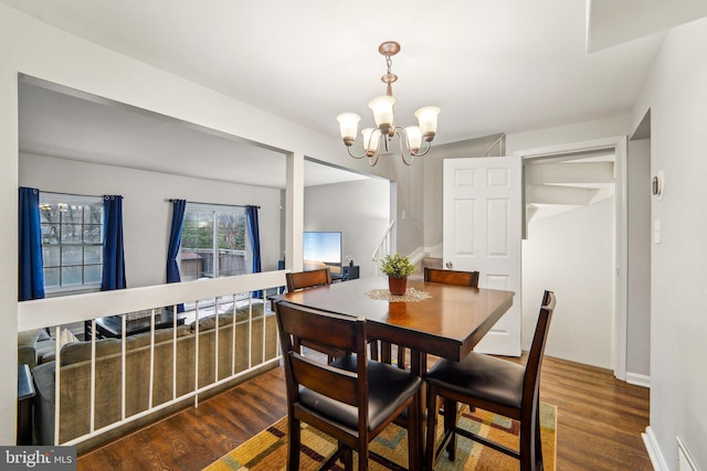 dining area with dark hardwood / wood-style floors and a notable chandelier