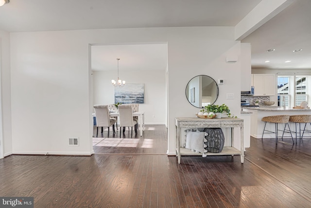 interior space with visible vents, baseboards, a notable chandelier, and hardwood / wood-style floors