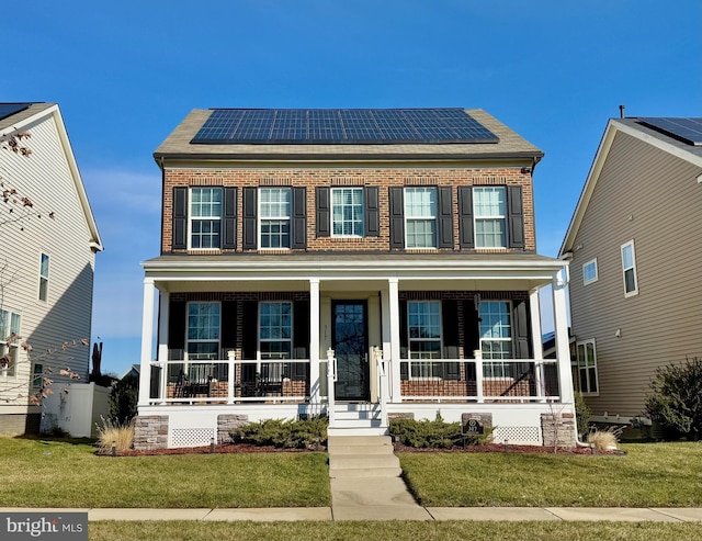 colonial inspired home with a front yard, solar panels, and a porch