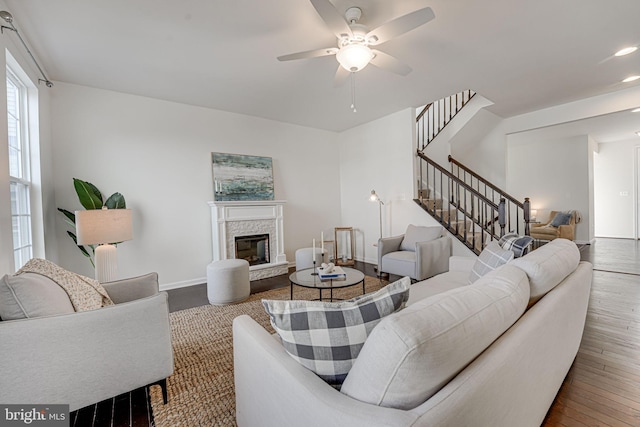 living room with a glass covered fireplace, stairs, baseboards, and wood-type flooring