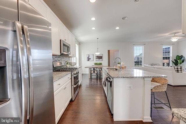 kitchen featuring tasteful backsplash, white cabinets, appliances with stainless steel finishes, and a sink