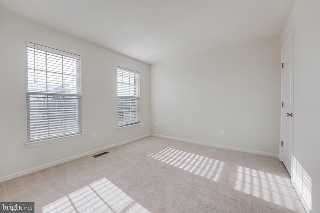 empty room with visible vents, light colored carpet, and baseboards