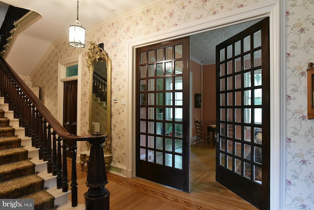 interior space featuring wood-type flooring, an inviting chandelier, french doors, and crown molding