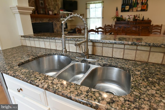 kitchen with a stone fireplace, sink, and white cabinets