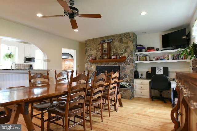 dining area with ceiling fan, light hardwood / wood-style floors, and a fireplace