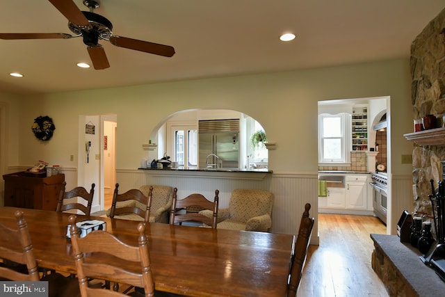 dining area with ceiling fan, sink, light wood-type flooring, and a fireplace