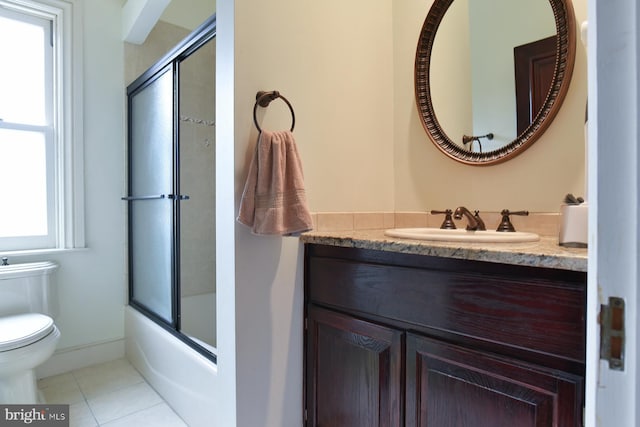 full bathroom with combined bath / shower with glass door, a wealth of natural light, vanity, tile patterned flooring, and toilet