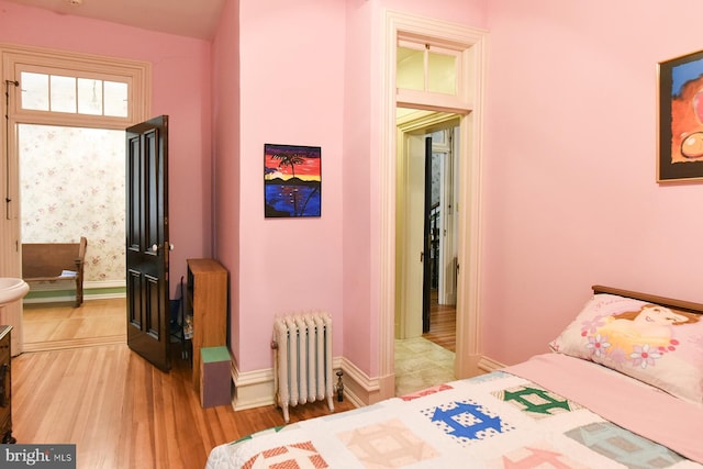 bedroom featuring radiator heating unit and light hardwood / wood-style flooring