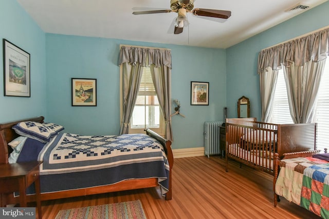 bedroom with ceiling fan, light wood-type flooring, and radiator