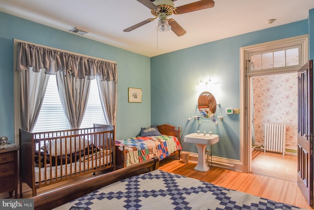 bedroom with radiator heating unit, hardwood / wood-style flooring, and ceiling fan