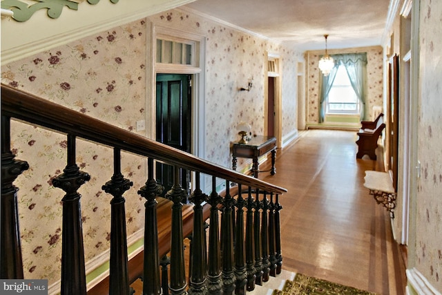 staircase with hardwood / wood-style floors, crown molding, and an inviting chandelier