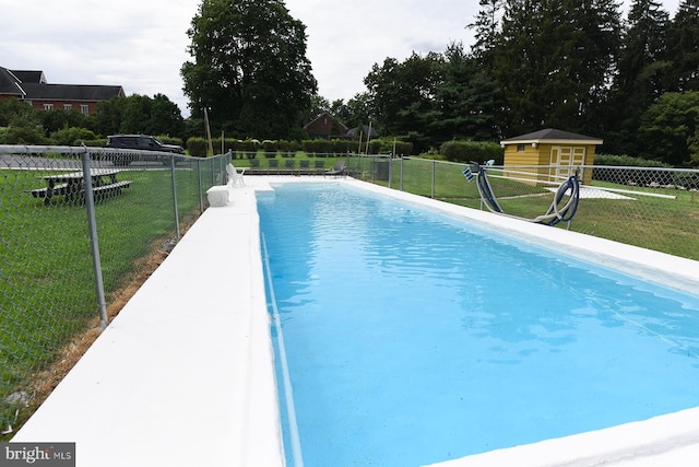 view of swimming pool featuring a lawn and an outbuilding