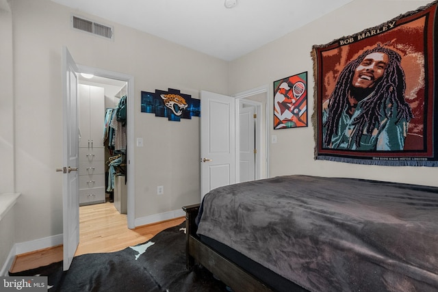 bedroom with hardwood / wood-style flooring and a walk in closet