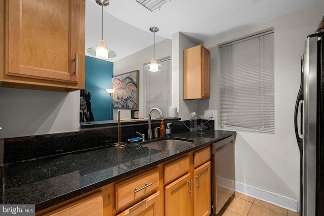 kitchen with pendant lighting, sink, light tile patterned floors, dark stone countertops, and stainless steel appliances