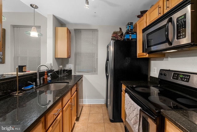 kitchen featuring pendant lighting, sink, dark stone countertops, stainless steel appliances, and light tile patterned flooring