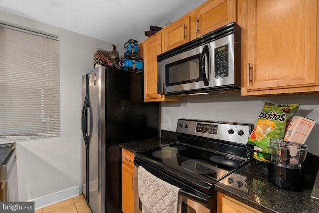 kitchen with dark stone countertops, appliances with stainless steel finishes, and light tile patterned floors