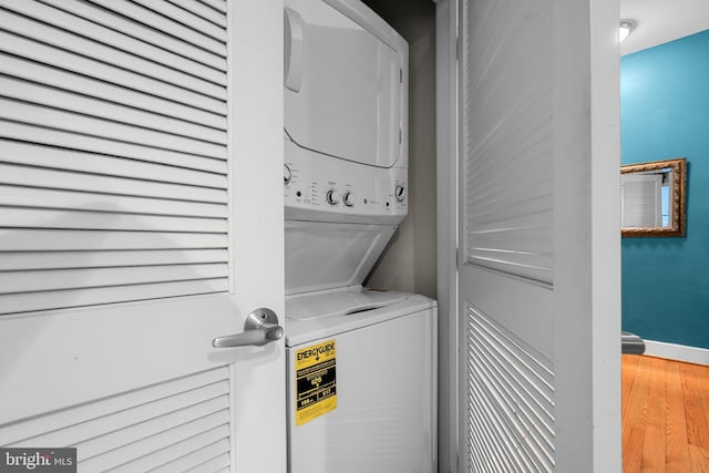 laundry area featuring stacked washing maching and dryer and hardwood / wood-style floors