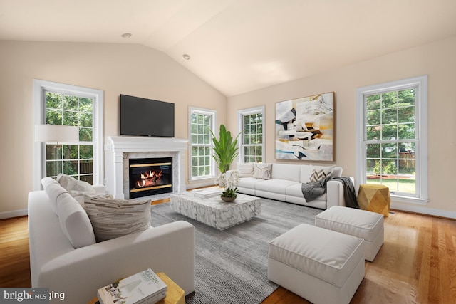 living room with lofted ceiling, a wealth of natural light, and light wood-style floors